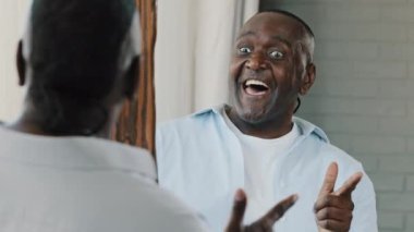 Close up senior comical man look in mirror reflection african american retiree confident 50s unshaven emotional adult businessman pointing forefinger at himself smiling toothy make facial wow reaction