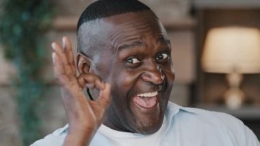 Close-up portrait elder african man positive grandpa ethnic father show consent sign okay hand gesture everything fine american adult retired customer client posing indoors satisfied with good service