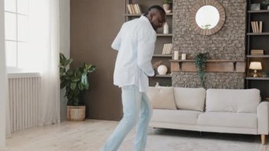 Enerjik, şanslı Afro-Amerikan yetişkin adam esnek, yaşlı dansçı modern breakdance öğreniyor müzik dansı yapıyor jimnastik yapıyor evde tek başına eğleniyor hip hop stilinde zaman geçiriyor.