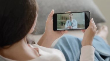 Omuz hizasında gezici bakış açısı üzerinden kadın hasta kadın doktorla uzaktan konuşma Coronavirus salgınında ev sağlık hizmetleri yardımlarından online tıbbi eğitim sunmaktadır.