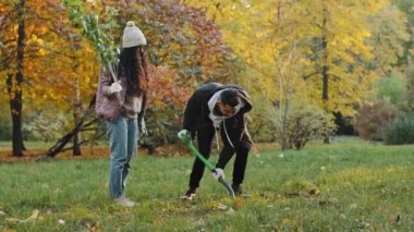 Young group people activists participate in social volunteer project for reforestation plant tree in autumn park care about nature environment protect ecology volunteers work outdoors planting plants