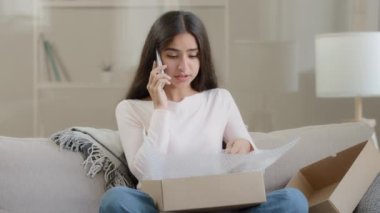 Hoşnutsuz Arap kadın kutu paketini açıyor çevrimiçi alışveriş mağazasından sahte sipariş hasarlı posta alıyor cep telefonu konuşmaları kötü teslimat servisine olumsuz geri bildirim şikayetleri