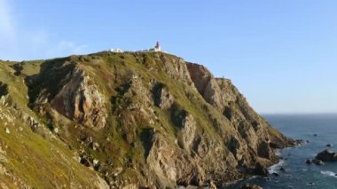 Drone flying over high hill rocks top view Atlantic ocean shores around cape Cabo da Roca in Sintra Portugal lighthouse westernmost point of Eurasian continent beautiful archipelagos natural scenery