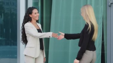 Friendly smiling young diverse female colleagues greeting each other by handshaking. Responsible recruiter shaking successful Indian woman hand at meeting, manager making great deal with customer