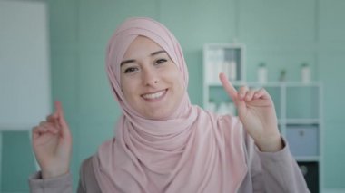 Arab Islamic Muslim girl in pink hijab businesswoman cheerful happy lady dancing move actively rhythmically listening to music woman in headscarf having fun in office celebrate victory winning success