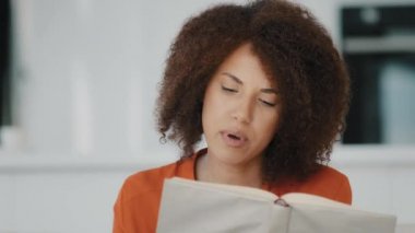 African American interested woman reading book loud home ethnic biracial student girl with curly hair learning distant knowledge education reads textbook exams enjoying hobby discover new information