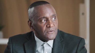 Ciddi bir Afrika portresi yaşlı olgun, dalgın, düşünceli, erkek yüzü kırışık ofiste düşünceli bir yönetici. Problemli çözüm planı hakkında kafa yoruyor. Kameraya gülümseyen dişli.