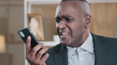 African old man senior mature male phone problem bad hearing confused 60s biracial businessman indoors answering call worries about bad mobile connection network cellular trouble broken smartphone