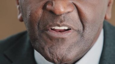 Extreme close up talking mouth of old senior biracial businessman, face part of speaking male wrinkled mature African leader having conversation talk to audience makes announcement motivational speech