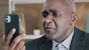 Yakından çekilmiş erkek portresi, Afrika kökenli 50 'li yaşlarda, orta yaşlı iş adamı, duygusal profesyonel, uzaktan kumandalı iletişim yöneticisi, cep telefonu kamerasıyla konferans görüntülerini arıyor.