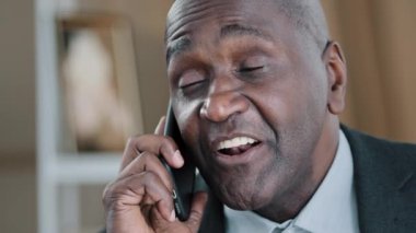 Yakın plan duygusal, yaşlı 50 'li yaşlarda buruşuk, erkek, yüz dostu iş adamı konuşan, cep telefonu konuşmaları cevaplayan. Portre Afrikalı patron, akıllı telefon, sohbet görüşmesi emrediyor.