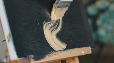 Female hand unrecognizable woman artist draws on black background with gold paint number eight infinity sign abstract image with acrylic creates minimalistic picture for art exhibition hobby drawing