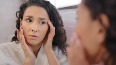 Headshot upset worried sad woman looking at mirror dissatisfied with condition of skin after new cosmetic substandard product frustrated girl worrying about first wrinkles in eye area and facial skin