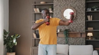 Sportive elderly african sportsman male fit healthy man in masculine athletic good physical shape doing domestic workout training make active exercises with dumbbells equipment at home pumping biceps