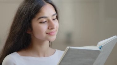 Dreamy girl student relaxed arab intelligent woman reading paper book classic romantic literature dreaming deep in positive thoughts enjoying interesting textbook resting in living room home education
