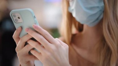 Unrecognizable young woman in medical face mask typing message on smartphone close up unknown girl using gadget browsing social networks chatting in messenger lady make booking online order on mobile