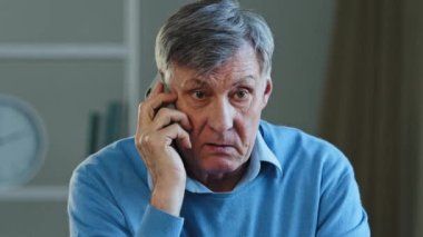 Close-up lonely pensioner talking on phone dissatisfied service elderly mature man yelling deceived aggressive angry grandfather emotionally speaking using smartphone sit in apartment grandpa swearing