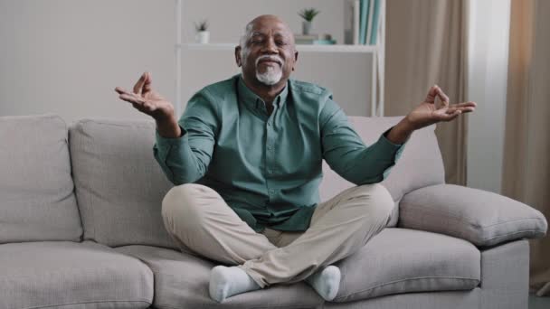 Ευτυχισμένος Ηλικιωμένος Αφροαμερικάνος Κάθεται Στον Καναπέ Στάση Λωτού Διπλωμένα Δάχτυλα — Αρχείο Βίντεο