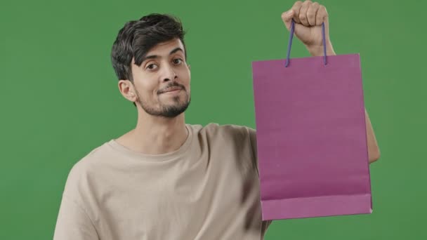 Счастливый Латиноамериканец Держит Сумку Покупок Позируя Студии Улыбающийся Молодой Арабик — стоковое видео