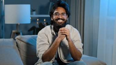 Close up happy arabian bearded man football male sitting at home evening at TV screen in dark living room and watching online match celebrating winning victory shout loud goal or win game. High