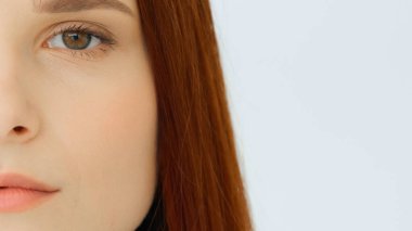 Close up female portrait red-haired sad caucasian woman half face perfect clean smooth skin after cosmetology beauty procedure young model with natural makeup looks at camera feminine equality concept