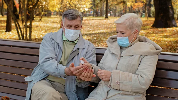 Coppia Anziana Maschere Mediche Autunno Parco Coniugi Disinfettare Mani Con — Foto Stock