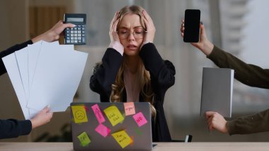 Front view overworked exhausted tired business girl woman worker manager in glasses holding head multitasking stress problem with work sitting table with laptop around calculator notebook papers phone