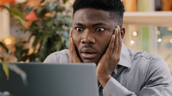 Close-up young businessman looking at laptop screen getting bad news surprised shocked man holding head found error incorrectness in electronic document virus in application loss important information