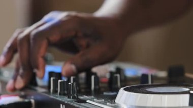 Close-up unrecognizable DJ man African male finger using mixer controller desk in club musical studio on stage celebrating turns up volume rotates buttons creates audio effects play live music disco