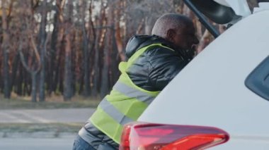 Üniformalı yaşlı Afro-Amerikan erkek kurye dışarıda mal alıyor. Yetişkin teslimatçı. Araba tamircisi yükleyicisinden karton kutuları indiriyor.