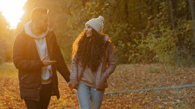 Mutlu genç çift güz parkında yürüyor doğada romantik bir akşam buluşması heyecanlı erkek kız arkadaşıyla iletişim kuruyor ilgi çekici bir hikaye anlatıyor arkadaşça sohbetin tadını çıkar