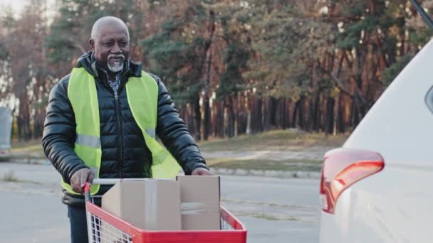 Пожилой Афроамериканец Работающий Магазине Таскает Тележку Картонными Коробками Машине Старый — стоковое видео