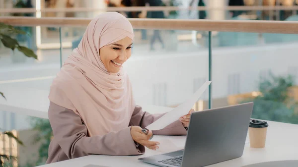 Young islamic woman sitting in cafe conducting online lesson talking on video conference using laptop distance employment muslim girl in hijab negotiating with client on webcam remote conversation