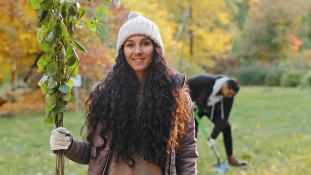 Happy Young Hispanic Woman Standing Outdoors Looking Camera Holding Sprout — Stock video