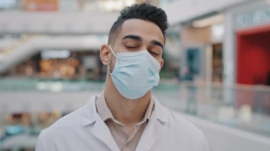 Hispanic Mexican Indian Arabian doctor therapist medical worker in mask tired exhausted frustrated overworked medic pretend shooting killing with non-contact thermometer like gun feel stress suicide