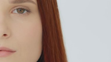 Close up female portrait red-haired sad caucasian woman half face perfect clean smooth skin after cosmetology beauty procedure young model with natural makeup looks at camera feminine equality concept