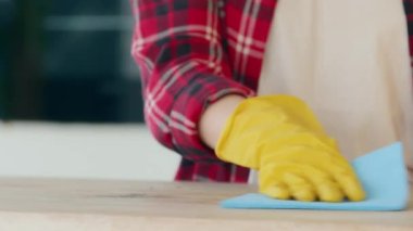 Unknown housewife female cleaner wears rubber yellow gloves keeping house neat washing table wet rag active wiping kitchen surfaces at home spraying detergent disinfecting liquid mopping dust indoors