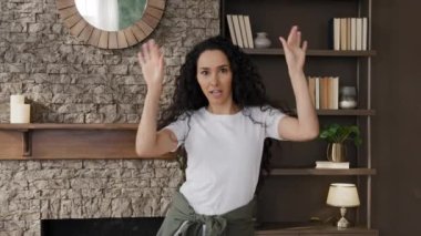 Young cheerful woman active dancing to music alone at home joyful happy girl funny falls on sofa in living room having fun on weekend relaxing smiling laughing enjoying relaxing on comfortable couch