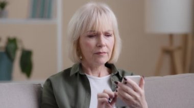 Frustrated senior lady Caucasian elderly woman with phone reads bad news in mobile message feel sad upset shock failure with smartphone app. Worried mature female user customer lost in online website