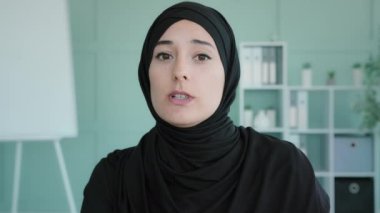 Webcam view female face portrait Islamism muslin woman in black hijab web teacher coach agent manager blogger speaks online chat video conference virtual class lecture serious business conversation