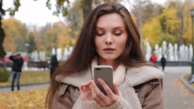 Surprised caucasian woman female citizen read online good news chatting remotely search for urban location on mobile phone modern device use internet city maps say wow win discounts in clothing store