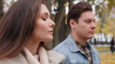 Caucasian girl offended by male lover on background young family couple standing outdoors ignoring each other looking different ways conflict misunderstanding sad woman thinking breakup with boyfriend
