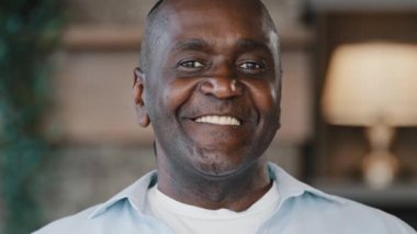 Happy african american optimistic senior friendly gentleman carefree ethnic adult man wink dark eyes flirting. Close up portrait elder businessman grandpa brunet male looking at camera smiling toothy