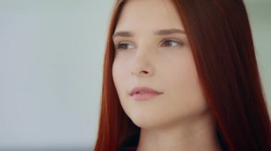 Close up caucasian lonely thoughtful woman redhead young 20s girl with long straight hair looking at distance deep in thoughts pondering new idea feel calmness melancholic mood expressing sad emotion