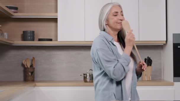 Ενεργός Γκρίζα Μαλλιά Ηλικιωμένη Γυναίκα Χρησιμοποιώντας Ξύλινη Κουτάλα Όπως Μικρόφωνο — Αρχείο Βίντεο