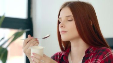 Close up caucasian woman redhead hungry girl vegetarian vegan tasting dairy dessert healthful morning snack delicious breakfast eat creamy yogurt dietary milk product dainty with minimal calorie diet