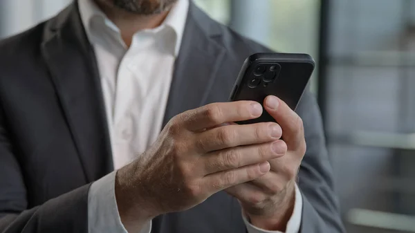 Moving footage close up male hands holding smartphone adult 40s man using mobile phone indoors. Bearded businessman technology user working in digital application gadget searching information online