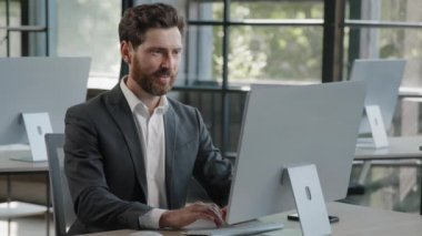 Happy success cheerful bearded 40s Caucasian adult man 30s businessman manager worker working with computer in office smile looking into camera with sign ok good idea done job approve agree advertise