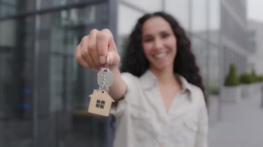 Happy smiling woman holding keys closeup portrait outdoors. Female realtor real estate agent lady selling property new building office dwelling skyscrapers girl homeowner rejoice relocation moving day
