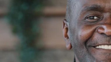 Close up joyful male human unshaved half face in details portrait mature african middle aged man healthy grandpa ethnic friendly grandfather pensioner looking at camera smiling toothy posing indoors